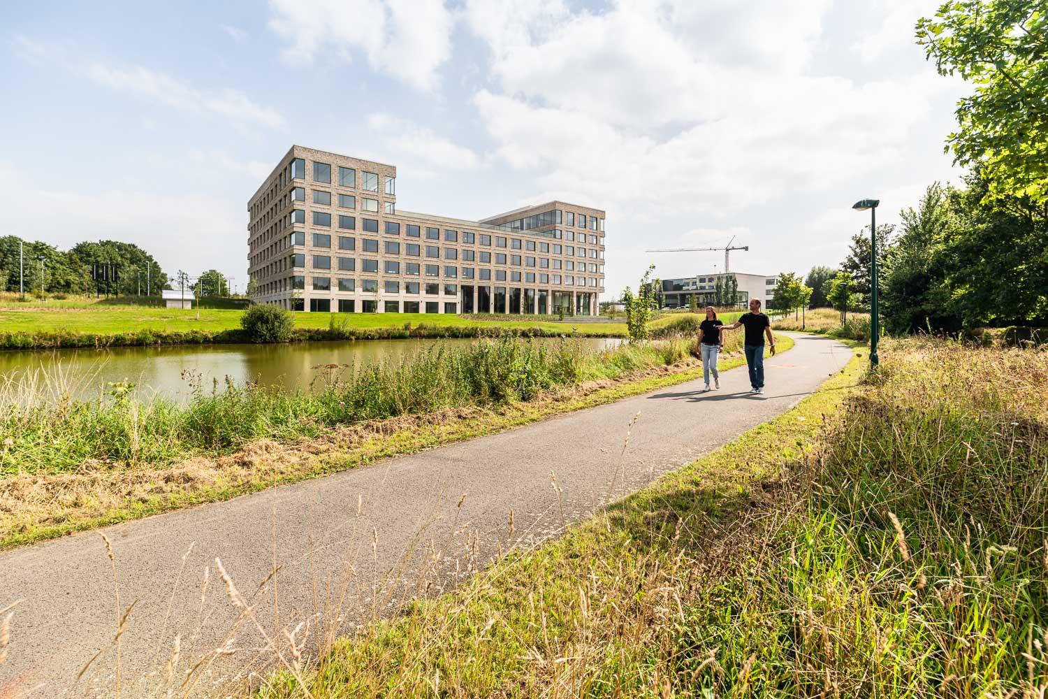 Wandelpad langs water met Kantoorgebouw Kortrijk Business Park op achtergrond